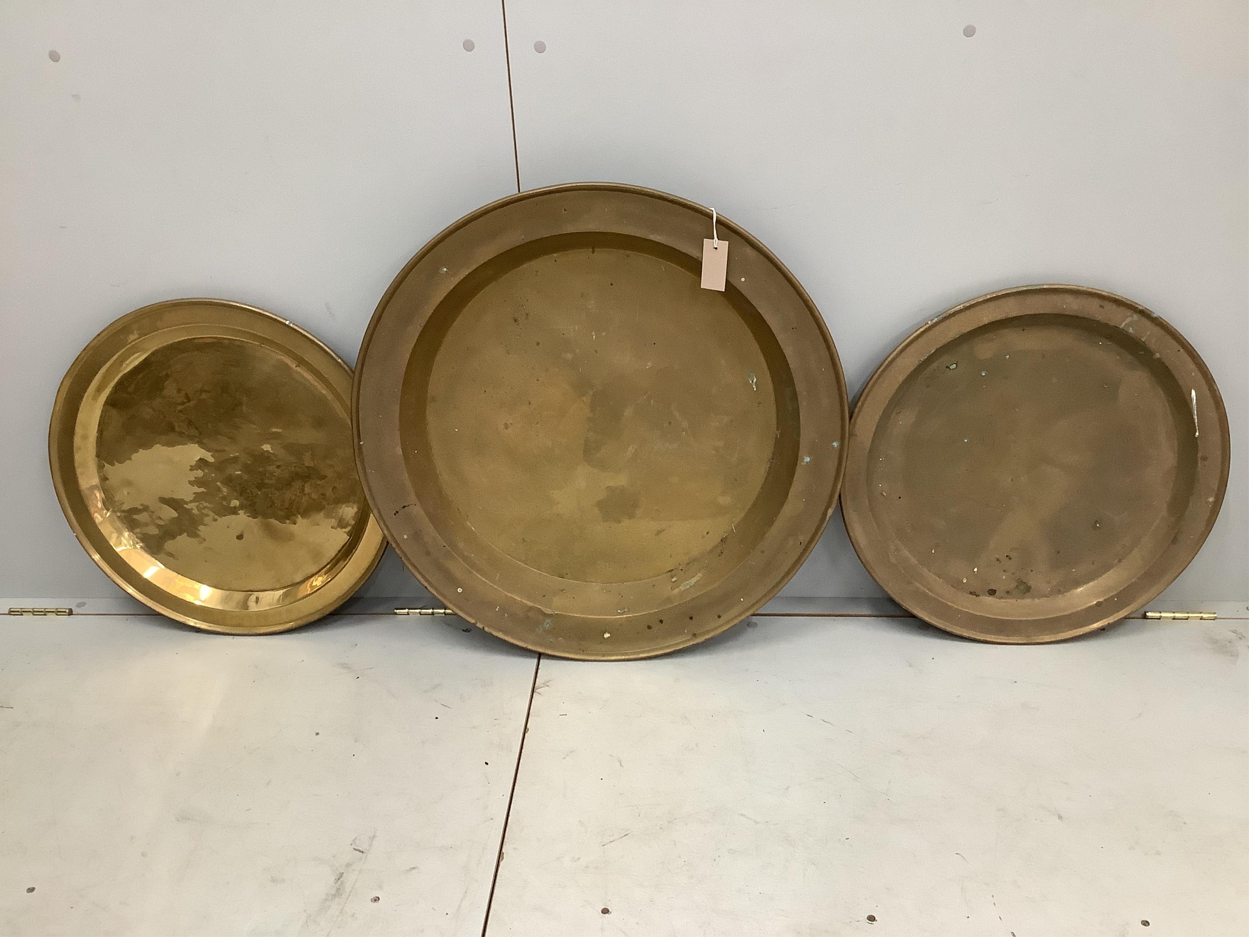 Three circular brass trays, largest diameter 72cm